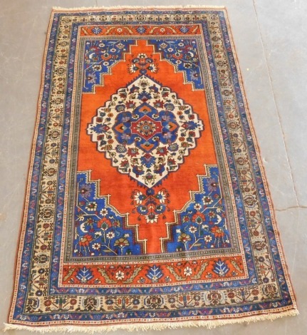 A Bakshaish orange and blue ground rug, with a central floral filled medallion and floral spandrels, within repeating floral and geometric borders, 304cm x 192cm.