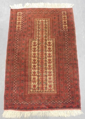 A Baluch red ground prayer rug, the cream mihrab filled with tree and floral motifs, within repeating floral and foliate borders, 172cm x 104cm.