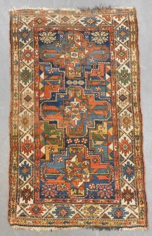 A Persian Karadja red ground rug, decorated with three central medallions, and half medallions, within repeating floral borders, 176cm x 98cm.