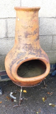 A clay chiminea, raised on an iron base.