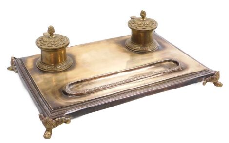 A late 19thC French polished bronze encrier, the pair of inkwells with floral embossed, hinged lids, raised on lion's paw feet, 34cm wide, 24.5cm deep.