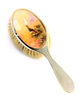 A George V silver mounted dressing table hairbrush, inset with a Royal Worcester porcelain plaque depicting grouse in landscape, mount obscures signature, Birmingham 1928, 19cm high.