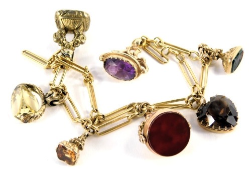 A Figaro link bracelet, with assortment of fob attachments, to include swivel moonstone and bloodstone, smoky quartz heart pendant, citrine swivel fob, a citrine set fob, a green agate carved fob set with head, and an amethyst fob, all in yellow metal col