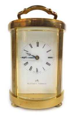 A 20thC brass cased carriage clock, the rectangular white enamel dial bearing Roman numerals for Matthew Norman, with eleven jewel unadjusted Swiss made movement for Matthew Norman Switzerland, numbered 1754, barrel movement, the case of circular form wit