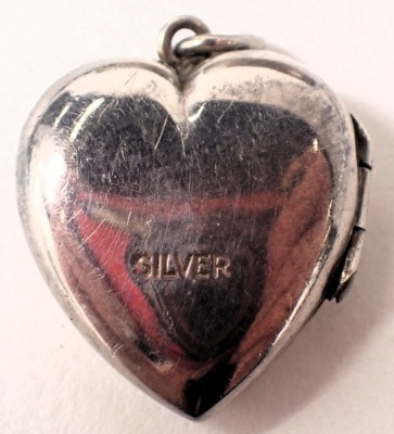 A group of silver jewellery, comprising a silver half hinged bangle with floral scroll decoration and safety chain, 6.5cm diameter, a silver crucifix pendant heart shaped locket and a fancy link bracelet with heart shaped padlock, 74.8g all in. (4) - 4