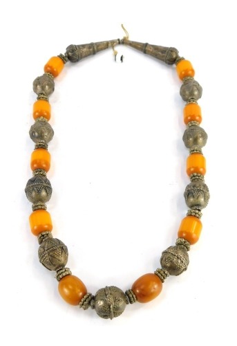 An Eastern inspired white metal and butterscotch amber necklace, the oblong beads of butterscotch amber 2cm long, with hammered and Eastern inspired white metal breaks, unmarked, on string strand, 76cm long overall, 248.2g all in. NB. We have specific ven