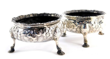 A pair of Victorian silver open salts, of cylindrical form, embossed with flowers, leaves, etc, raised on three hoof feet, London 1851, 4.23oz, 7cm diameter.