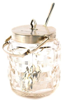 A George V cut glass and silver mounted condiment pot, of cylindrical form with silver mount and lid, ring handle, London 1915, 12cm high, together with preserve spoon, Sheffield 1997. (2)