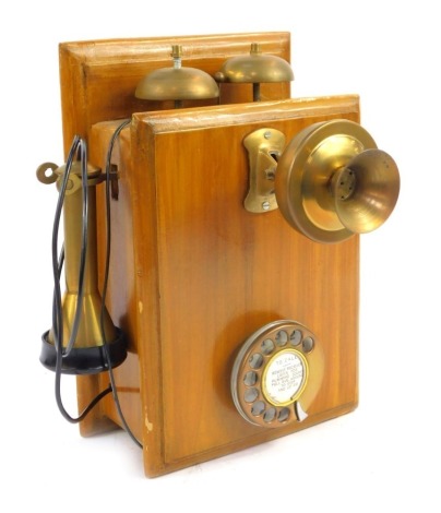 A vintage wall mounted telephone, with earpiece and corded speaker, on a stained wooden mount, 29cm high.