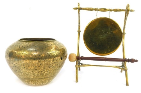 A late 19th/early 20thC brass dinner gong, with beater with turned wooden handle, 30cm high, together with an Eastern brass vase with incised decoration depicting animals, foliate motifs, etc., of compressed cylindrical form, 17cm high. (AF)