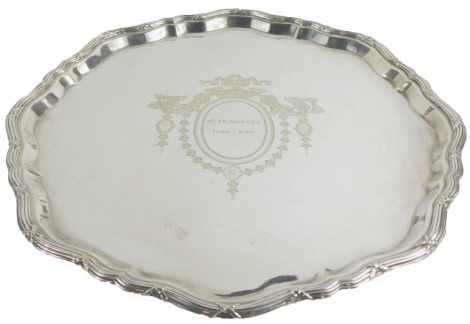 A Mappin and Webb silver plated salver, with shaped border, decorated centrally with St Dunstans 1960-1980 amid bows, swags, floral motifs, etc., 36cm diameter.