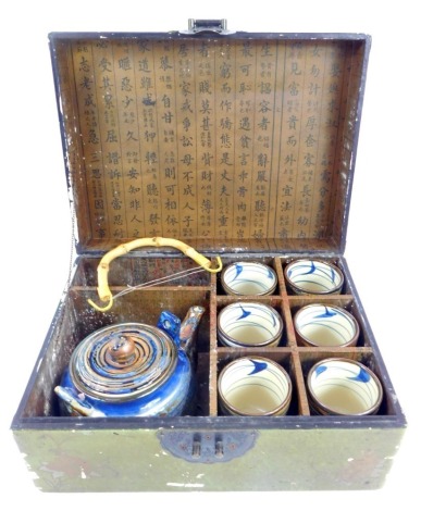 A Japanese porcelain Sake set, each cup decorated with raised mottled blue decoration against a pale terracotta ground, with teapot, contained in a green faux leather box, 30cm wide.