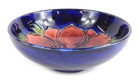 A Moorcroft pottery dish, decorated centrally with a flower against a blue ground, impressed marks to underside, 11.5cm diameter.