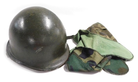 A WWII US Army steel helmet, with camouflaged cloth cover.