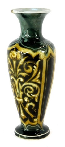 A late 19thC Doulton Lambeth stoneware vase, of shouldered cylindrical tapering form with flared neck, decorated with amber and white coloured scrolls, within brown ground reserves, against a dark green ground, impressed marks to underside, No 1884, 17cm 