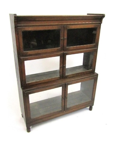 A 1920s oak sectional bookcase by Minty Limited of Oxford, with three glazed compartments, with stepped lower compartment, on low turned feet, 119cm high, 89cm wide, 30cm deep.