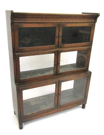 A 1920s oak sectional bookcase by Minty Limited of Oxford, with three glazed compartments, with stepped lower compartment, on low turned feet, 119cm high, 89cm wide, 30cm deep.