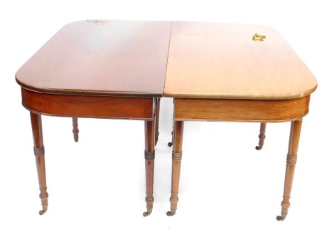 An early 19thC mahogany D end dining table, with plain frieze raised on slender tapered legs with ring collars and brass castors, 73cm high, the top 134cm x 120cm.