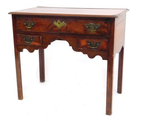 A George III mahogany low boy, with thumb moulded top and fitted with one long drawer with two short drawers to the shaped apron, having brass handles, on chamfered square legs, 70cm high, 82cm wide, 47cm deep.