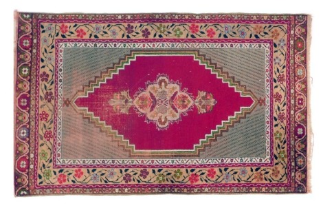 An Eastern red ground rug, decorated with central lozenge within multiple floral borders, 107cm x 174cm. (AF)