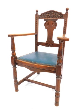 An early 20thC oak open armchair, carved cresting rail and studded vinyl seat.