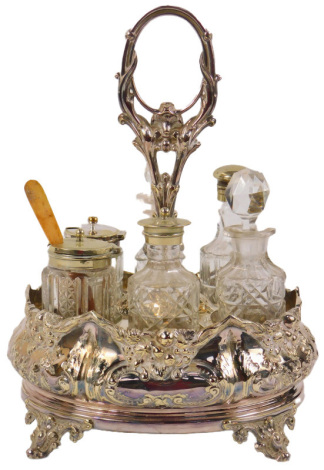 A late 19th/early 20thC silver plated cruet, with central ring handle, with six sections for bottles, the base of oval form embossed with foliate and fruit decoration, on four scroll cast feet, together with six bottles, the stand 29cm high.