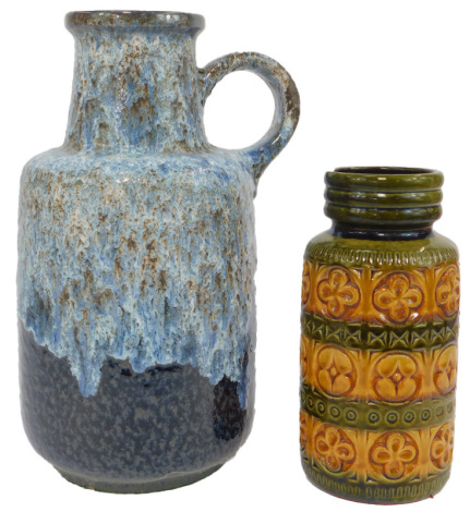 A West German pottery flagon, of cylindrical shouldered form, with ring handle, in mottled blue glaze, 39cm high, together with a vase with impressed floral decoration decorated in bands of green and amber, 27cm high.