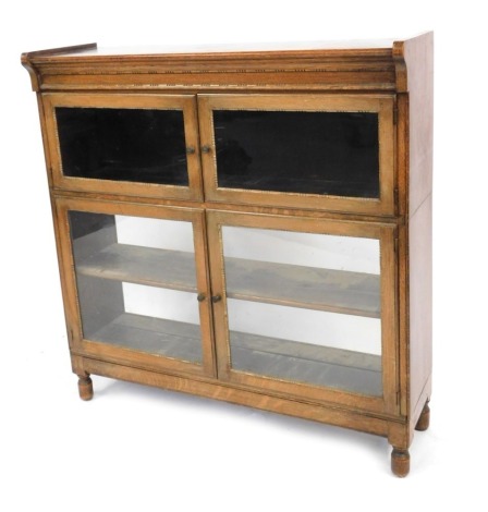 A 1920s oak sectional bookcase by Minty Limited of Oxford, with two glazed compartments, raised on low turned feet, 92cm high, 89cm wide, 27cm deep.