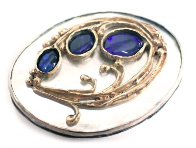 A Danish Art Nouveau oval brooch, with rub over border on mother of pearl backing shell, set with three fire opals, with leaf vine back, white metal stamped STG Sill, and bearing the initials MV, with pendant mount, safety chain, and single pin back, 5.5c