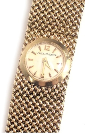 A Jaeger-LeCoultre 9ct gold wristwatch, with a small circular cream coloured watch head, 1cm diameter, on cross weave design bracelet, serial number 5599, 41.8g all in, in later green box.