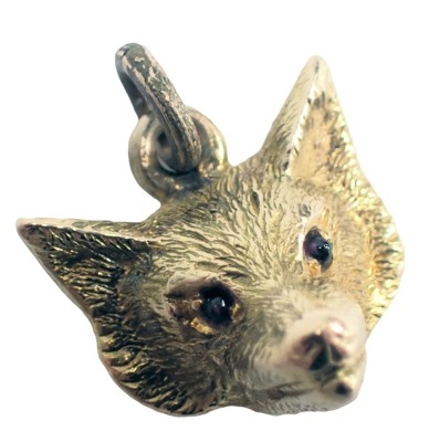 A fox head pendant, set with garnet eyes, yellow metal stamped 14ct, 1cm high, 3.6g.