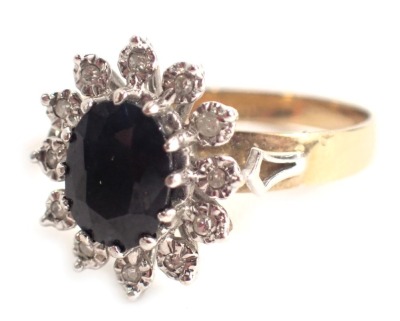 A 9ct gold cluster ring, centred by oval sapphire in claw setting, with outer petals each with illusion set tiny diamonds, in platinum setting on a yellow metal band, ring size O½, 2.7g all in.