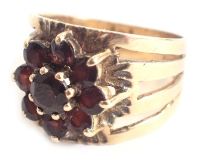 A garnet cluster ring, the garnet cluster in claw setting, with hammered and etched design ring head, on four splayed shoulder, yellow metal with rubbed hallmarked believed to be 9ct, ring size O½, 5.5g all in.