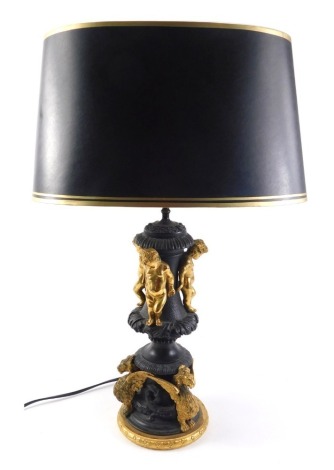 A continental bronze and gilt metal lamp base, applied with three putti, winged lions, etc., on a laurel wreath base, 54cm high, including blackened gilt shade.