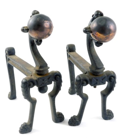 A pair of early 20thC black painted cast iron and copper fire dogs, each modelled with a ball and claw. (AF)