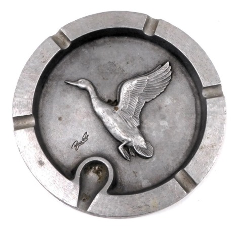 A large 20thC aluminium ashtray, cast centrally with a flying duck, indistinctly signed Bruce?, 24cm diameter.