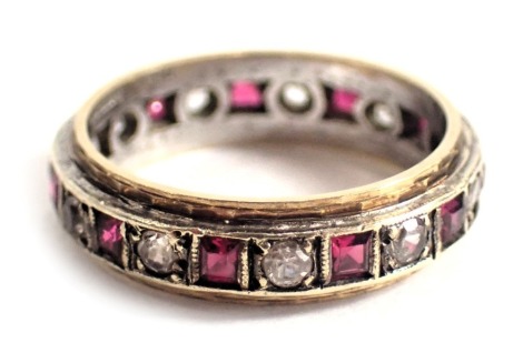 A diamond and ruby set eternity ring, with arrangement of round brilliant cut diamonds and square cut rubies, yellow metal setting, stamped 9ct, ring size M, 3.4g all in.