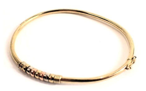 A 9ct gold hinged bangle, of bicolour central link design, 6.5cm diameter, 5g, boxed.