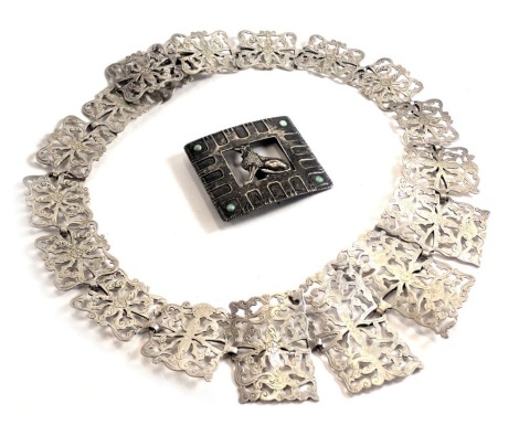 A silver plated graduated nurses buckle of scroll design, and an eastern buckle with central leopard inset with stones, white metal unmarked. (2)