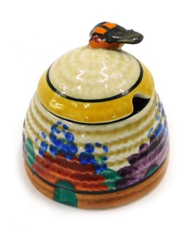 A Clarice Cliff Bizarre honey jar and cover, decorated with the Gay Day pattern, 7cm high.