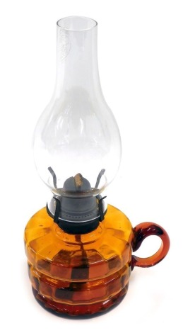 A Victorian amber tinted glass oil lamp, with handle, funnel and chimney, 32cm high.