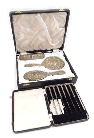 A silver mounted three piece dressing table set, comprising hand mirror, hand brush and brush, stamped sterling, in fitted case, and a set of six silver handled dessert knives in a fitted case.