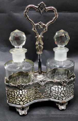 A Victorian silver plated two bottle cruet stand, containing a pair of cut glass bottles with faceted stoppers, the frame with pierced decoration, raised on four scroll feet, 28.5cm high.