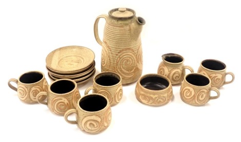 A studio pottery coffee set, comprising six cups and saucers, milk jug, sugar bowl, and coffee pot, on a beige ground.