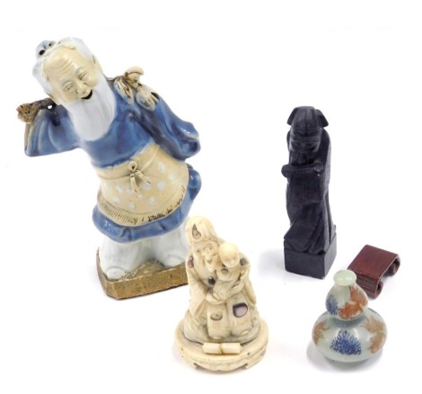 An oriental Japanese bone carved okimono modelled as an immortal with a child, embellished in mother of pearl, a porcelain figure of a gentleman, porcelain snuff bottle, and a further figurine. (4)