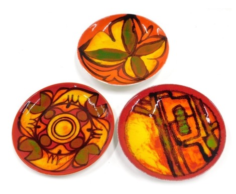 Three Poole pottery Delphis style shallow dishes or plates, each decorated in shades of red, green, orange and yellow, printed marks to underside, 20cm diameter.