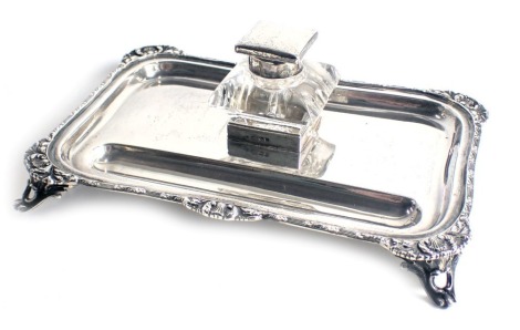 A George V silver inkstand, the border cast with scrolls, shells, etc., with pen tray and glass inkwell with silver mounts, Birmingham 1918, weighable silver 11.16oz, 23cm wide.