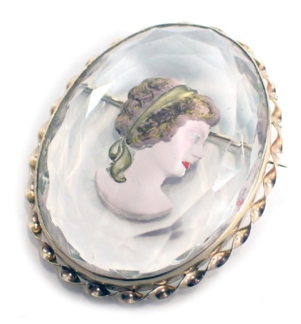 A portrait brooch, of oval crystal design, with painted decoration of a female, in yellow metal border, unmarked, with single pin back, 4cm x 3cm.