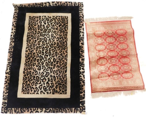 A modern leopard print machine woven rug, with black borders, on a cream ground, 107cm wide, 164cm tall and an oriental style machine woven cotton rug 68cm wide, 109cm tall. (2)