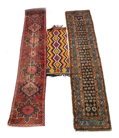 A Persian runner with a design of medallions and gulls, and other multicoloured devices, with three narrow borders, AF, 71cm x 270cm, another Persian runner on a red ground, 66cm x 282cm, (both AF), and a small kilim rug, 52cm x 122cm.